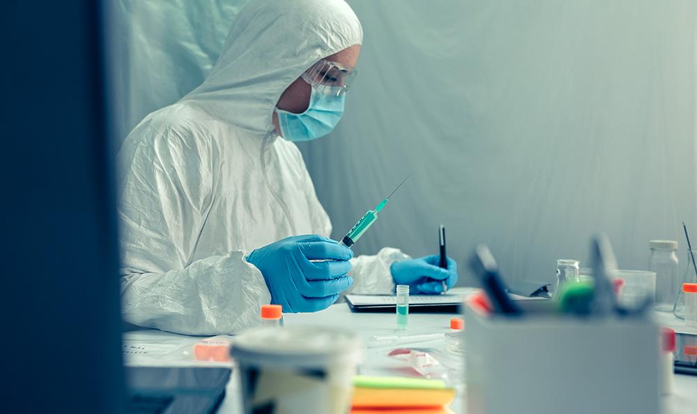 female scientist with bacteriological protection suit investigating a vaccine in the laboratory